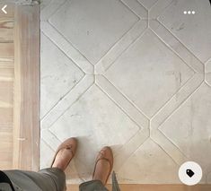 a person standing on the floor with their feet up in front of a tile wall