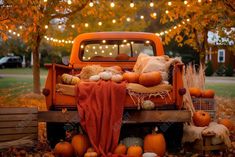 an orange truck with pumpkins and other decorations on the bed in front of it