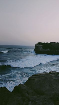 the ocean waves are crashing against the rocks