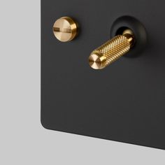 two gold knobs on the side of a black wall