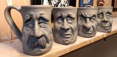 three mugs with faces on them sitting on a shelf