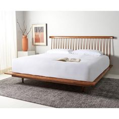 a white bed with wooden headboard and foot board on carpeted floor next to window