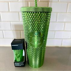 a green starbucks cup next to a black box