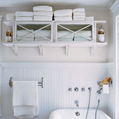 a white bath tub sitting next to a toilet under a shelf with towels on it