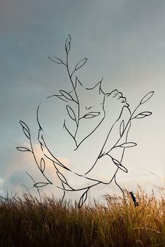 a drawing of a woman's face on top of a tree branch in the grass