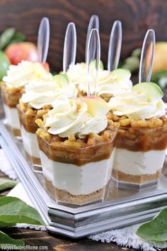 small desserts with apple slices and whipped cream on top are arranged on a glass platter