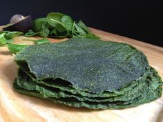 a pile of spinach leaves sitting on top of a wooden cutting board