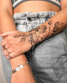 a woman with tattoos on her arm holding onto another person's arm and wearing bracelets