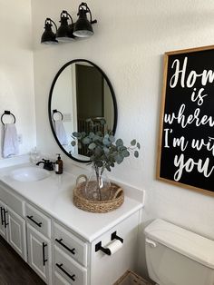 a bathroom with a sink, mirror and toilet in it's corner next to a chalkboard sign