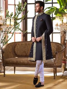 Item Contains:  Sherwani Kruta Pyjama  Shawl and Shoes  Fabrics :   Premium luxury suiting Colours :  Black base and golden dabka work White chudidaar pyjama  Style and Designs : Sherwani has mandarin collar and long sleeves with a full button placket asymmetric hem and multiple slits and it has golden hand work on neck (collar) Kurta has mandarin collar and long sleeves with a full button placket symmetric hem and multiple slits  White coloured churidar has a drawstring closure with nara Black Traditional Drape Black Kurta For Groom, Traditional Black Kurta For Groom, Black Sherwani For Groom On Eid, Black Traditional Wear With Resham Embroidery For Groom, Black Dabka Sherwani For Groom, Black Traditional Wear With Resham Embroidery For Wedding, Black Sherwani For Groom For Festivals, Black Sherwani For Groom At Festivals, Black Traditional Wear For Groom On Eid