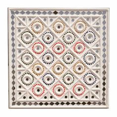 a white tile with multicolored circles in the center and an intricate design on it