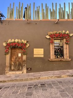 an old building with two wooden doors and flowers on the windows