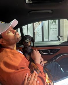 a man sitting in the back seat of a car with his dog on his lap