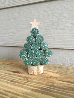 a small green christmas tree made out of cookies on top of a wooden table next to a white wall