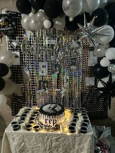 a table topped with a cake surrounded by black and white balloons