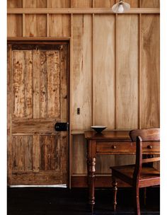 a room with wooden paneling and a chair next to a table in front of a door