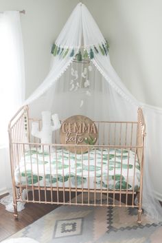 a baby crib in a white room with green bedding and a canopy over it