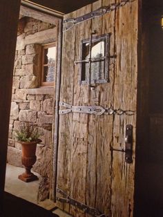 an open door to a stone building with a potted plant