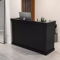 a black reception table with a laptop on it in front of a mirror and door