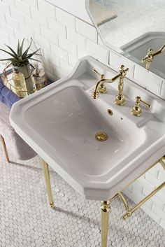 a white sink sitting next to a mirror on top of a tiled floor in a bathroom