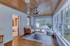 a living room filled with furniture and lots of windows next to a wooden flooring