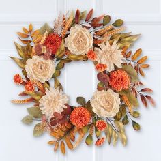 a wreath with flowers and leaves hanging on the front door to decorate it for fall