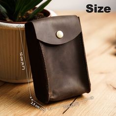 a small brown leather case sitting on top of a table next to a potted plant