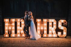 a bride and groom standing in front of the words mr and mrs lit up at night