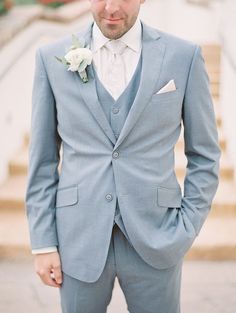 a man in a blue suit and white flower boutonniere standing on steps