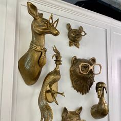 brass figurines and animal heads are displayed on a white cabinet door with glasses