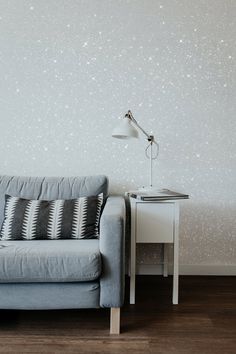 a blue couch sitting next to a white table with a lamp on top of it