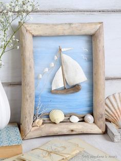 a wooden frame with a sailboat and seashells