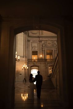 a bride and groom standing in an archway at night