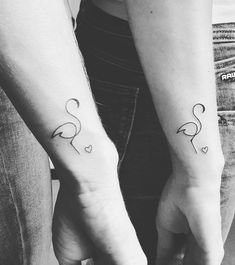 two people holding hands with tattoos on their arms and one has a small heart in the middle