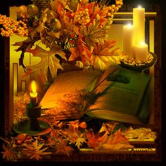 an open book sitting on top of a table next to candles and autumn leaves in front of it