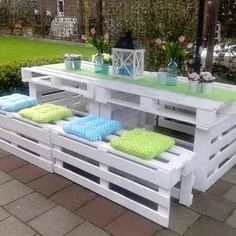 an outdoor table made out of pallets with pillows on the bottom and green cushions