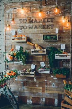 a market with lots of vegetables and fruits hanging on the wall next to wooden crates