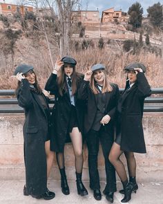 four young women dressed in business attire posing for a photo with hats on their heads