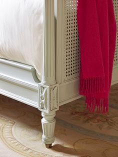 a white bed with a red blanket on it's headboard and foot board