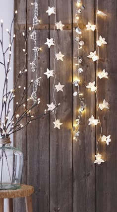 a tree with white stars hanging from it's branches next to a wooden fence