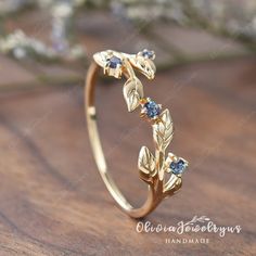 a gold ring with leaves and diamonds on it sitting on top of a wooden table