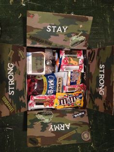 a box filled with snacks and candy on top of a green table covered in camouflage