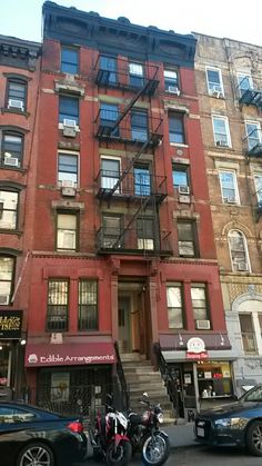 two motorcycles parked in front of an apartment building with fire escapes on the second floor