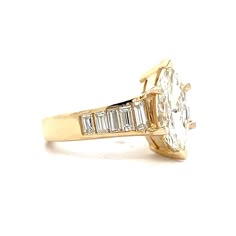 a yellow gold ring with an oval cut diamond surrounded by baguetts of diamonds