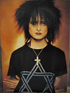 a woman with black hair and cross on her shirt