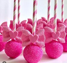 pink cake pops with bows and hearts on them are lined up in front of each other