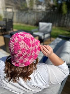 a woman wearing a pink crocheted hat on top of her head and back