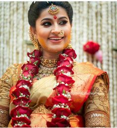 a woman in a red and gold outfit with flowers on her head smiles at the camera