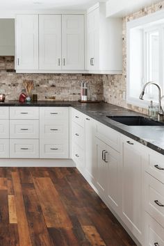 a kitchen with white cabinets and wood floors