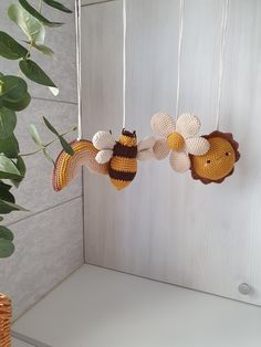 three crocheted honeybees hanging from strings next to a potted plant